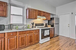 Una cocina con armarios de madera, un refrigerador de acero inoxidable, una estufa y un microondas.