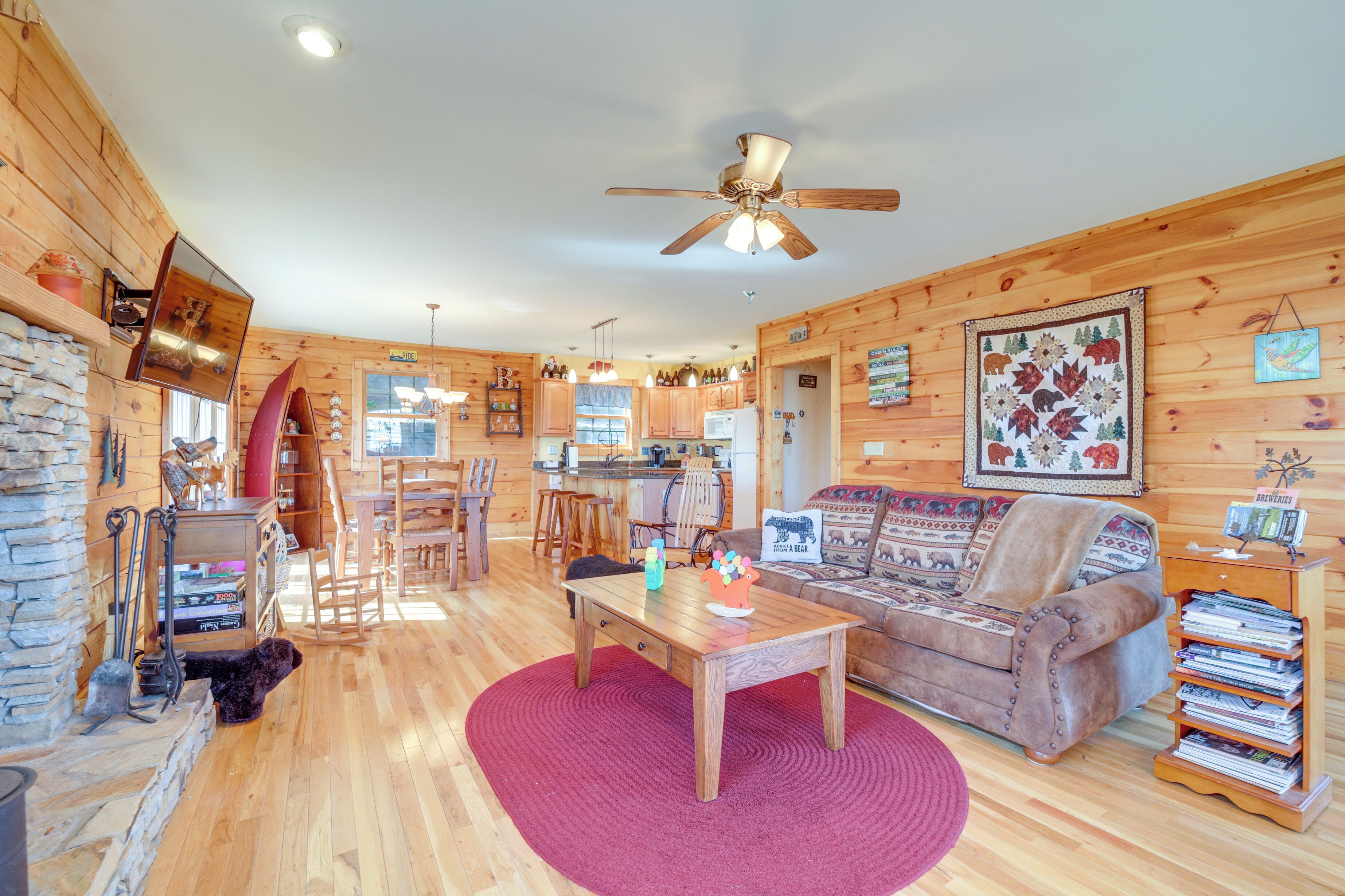 A cozy log cabin interior with a wooden dining table, a sofa, and a bookshelf.