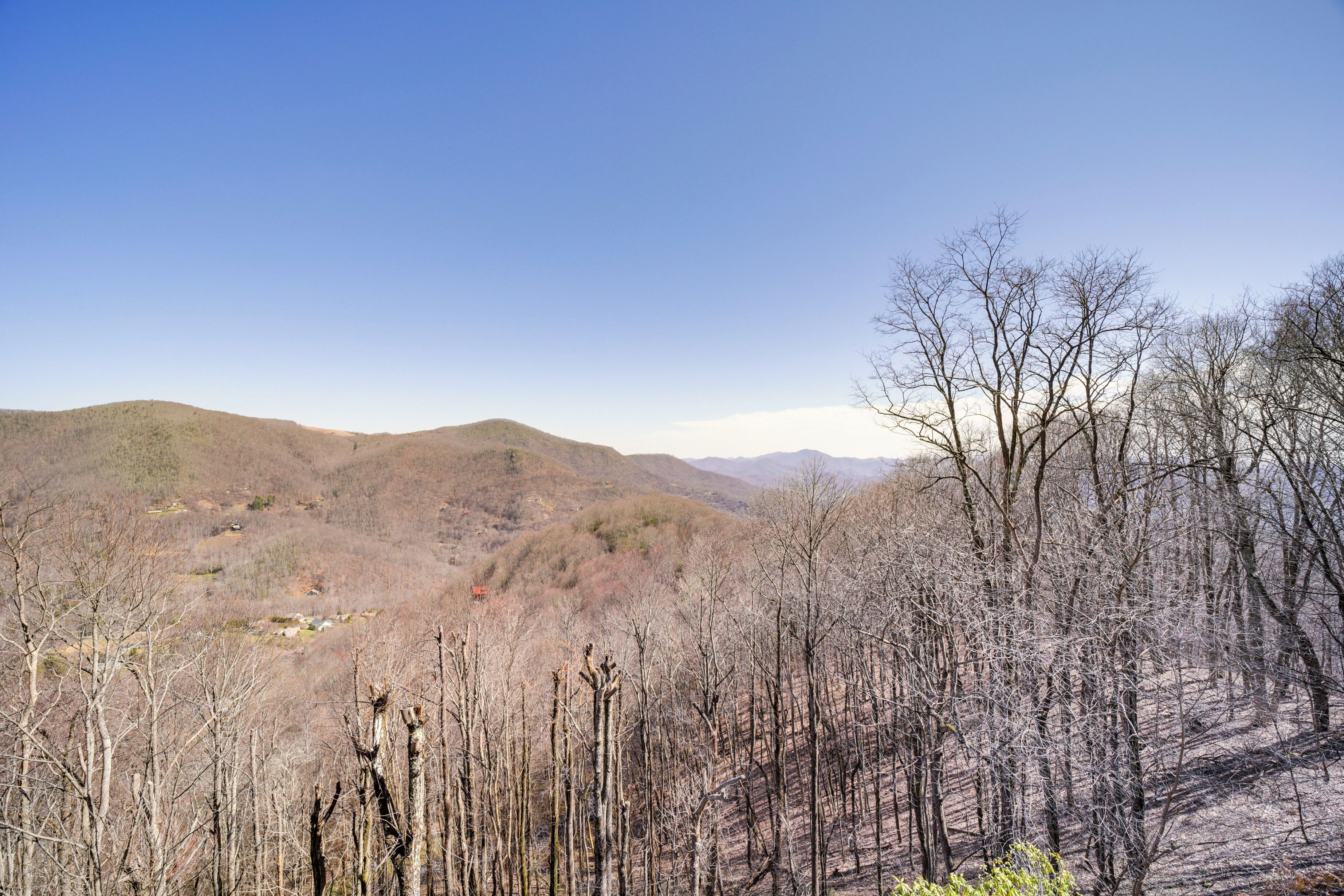 Un paysage montagneux, avec quelques arbres clairsemés et un ciel dégagé.
