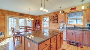 Una cocina tipo cabaña de madera con una isla central, armarios de madera y un ventanal grande.