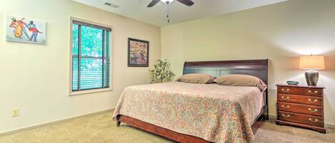 A bedroom with a bed, a ceiling fan, a dresser, and a window with blinds.