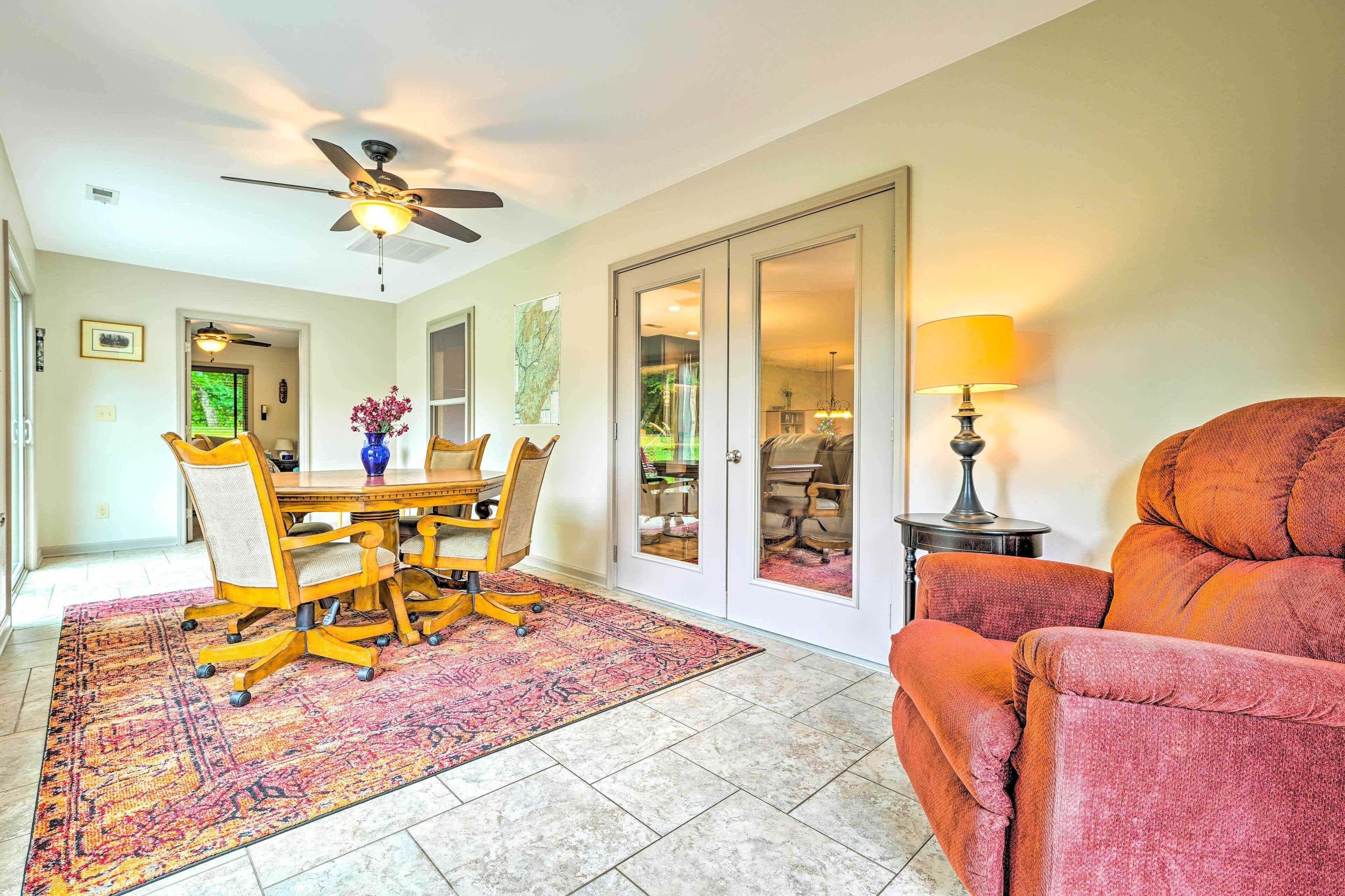 A dining area with a table and chairs, a ceiling fan, and a rug.
