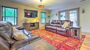 A living room with leather sofas, a red patterned rug, a TV, and a decorative hanging light.