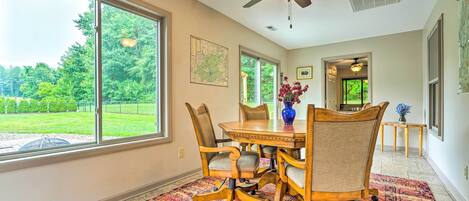 A dining area with a large window, a ceiling fan, and a patterned rug.