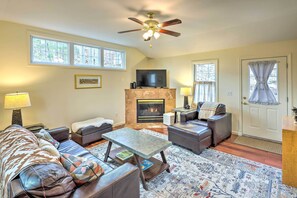 A living room with a fireplace, leather sofas, a coffee table, and a ceiling fan.