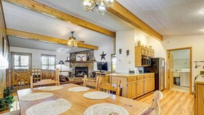 A spacious kitchen with wooden cabinets, a dining table with placemats, and a stone fireplace.