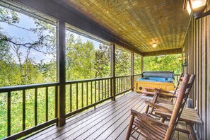 A wooden deck with a hot tub and seating area, overlooking a forested area. - Hot Tub & Deck: Woodsy Sevierville Cabin (Sevierville)