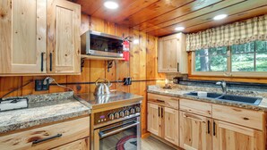 A wooden cabin kitchen with a built-in oven, a microwave, a sink, and a window with a view of the outdoors. - Dock & Lake Access! St Germain Getaway (St Germain)