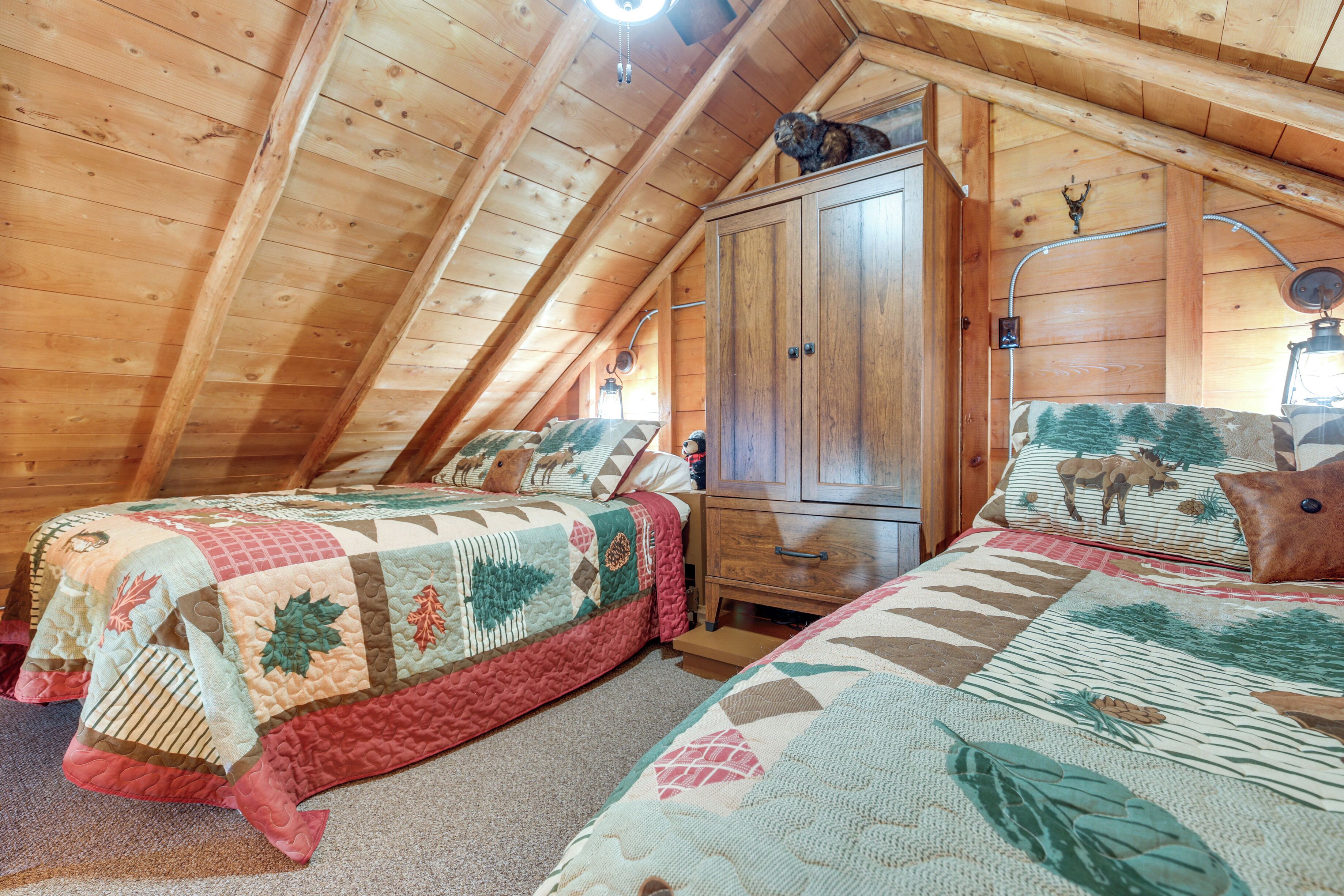 A cozy attic bedroom with two beds, a wooden wardrobe, and a rustic decor.