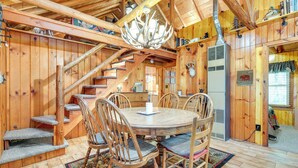 A wooden cabin interior with a round dining table, wooden chairs, a staircase, and a chandelier. - Dock & Lake Access! St Germain Getaway (St Germain)