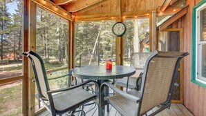 A covered outdoor seating area with a round table, chairs, and a clock on the wall. - Dock & Lake Access! St Germain Getaway (St Germain)