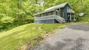A two-story house with a porch, surrounded by a forest. - Secluded Cabin w/ Porch - 7 Miles to Lake Chatuge! (Hayesville)