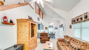 A cozy living room with a fireplace, wooden furniture, a sofa, and a dining area with a table and chairs. - Secluded Cabin w/ Porch - 7 Miles to Lake Chatuge! (Hayesville)