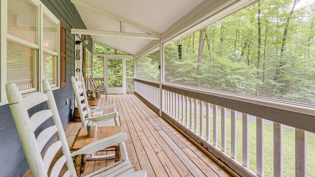A covered porch with wooden chairs and a table, overlooking a forested area. - Secluded Cabin w/ Porch - 7 Miles to Lake Chatuge! (Hayesville)
