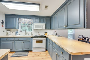 A kitchen with blue cabinets, a white stove, and a wooden countertop. - Secluded Cabin w/ Porch - 7 Miles to Lake Chatuge! (Hayesville)