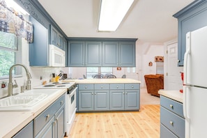 A kitchen with blue cabinets, a white refrigerator, and a wooden floor. - Secluded Cabin w/ Porch - 7 Miles to Lake Chatuge! (Hayesville)