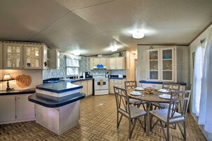Una cocina con isla central, sillas de madera y una mesa de comedor.