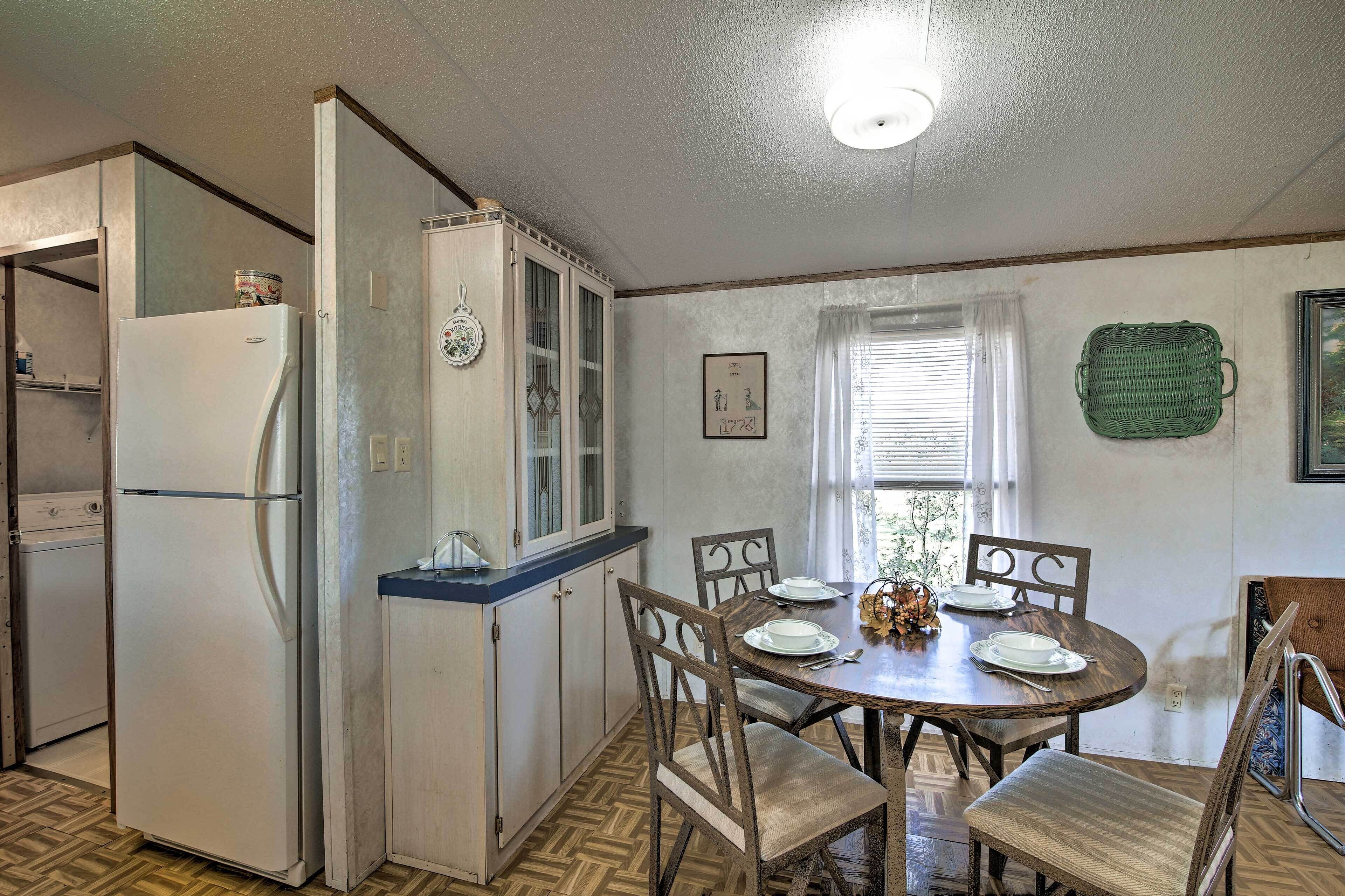 A compact kitchen with a refrigerator, wooden cabinets, and a dining table set for four.