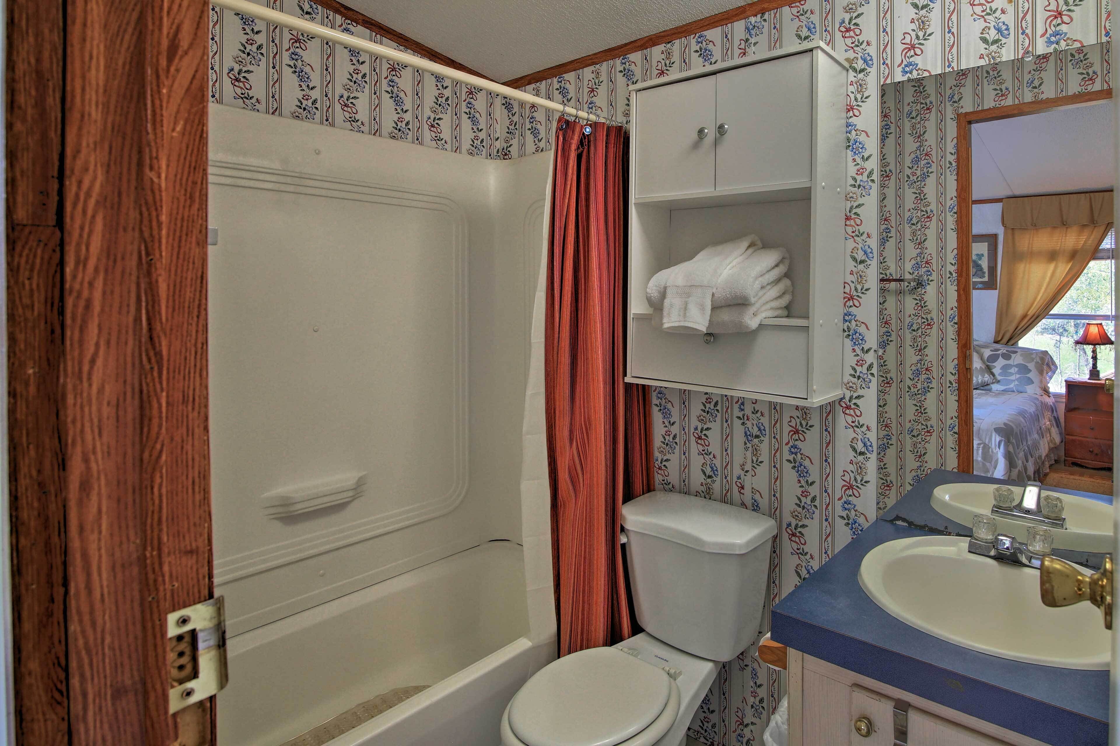 A bathroom with a bathtub, toilet, and a sink with a mirror.