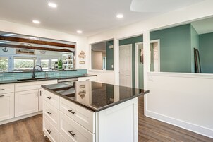 Una cocina moderna con armarios blancos, encimera de granito y vistas al exterior.