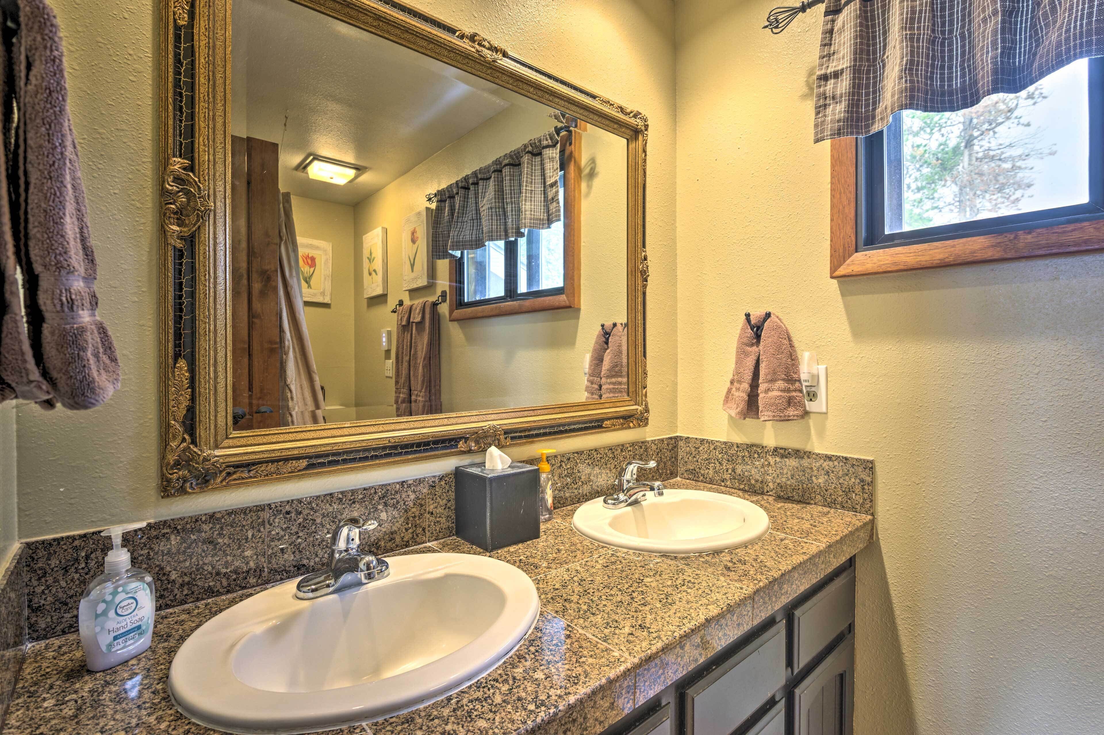 A bathroom with two sinks, a large mirror, and towels hanging on the wall.