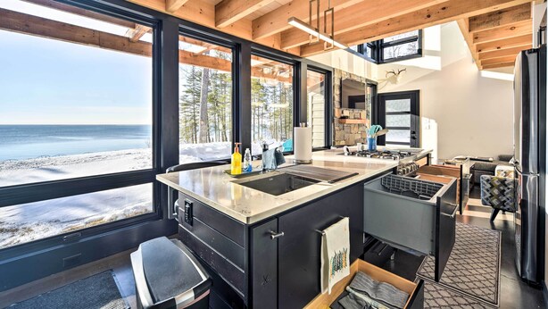 Een moderne keuken met een groot eiland, inbouwapparatuur en uitzicht op het strand.