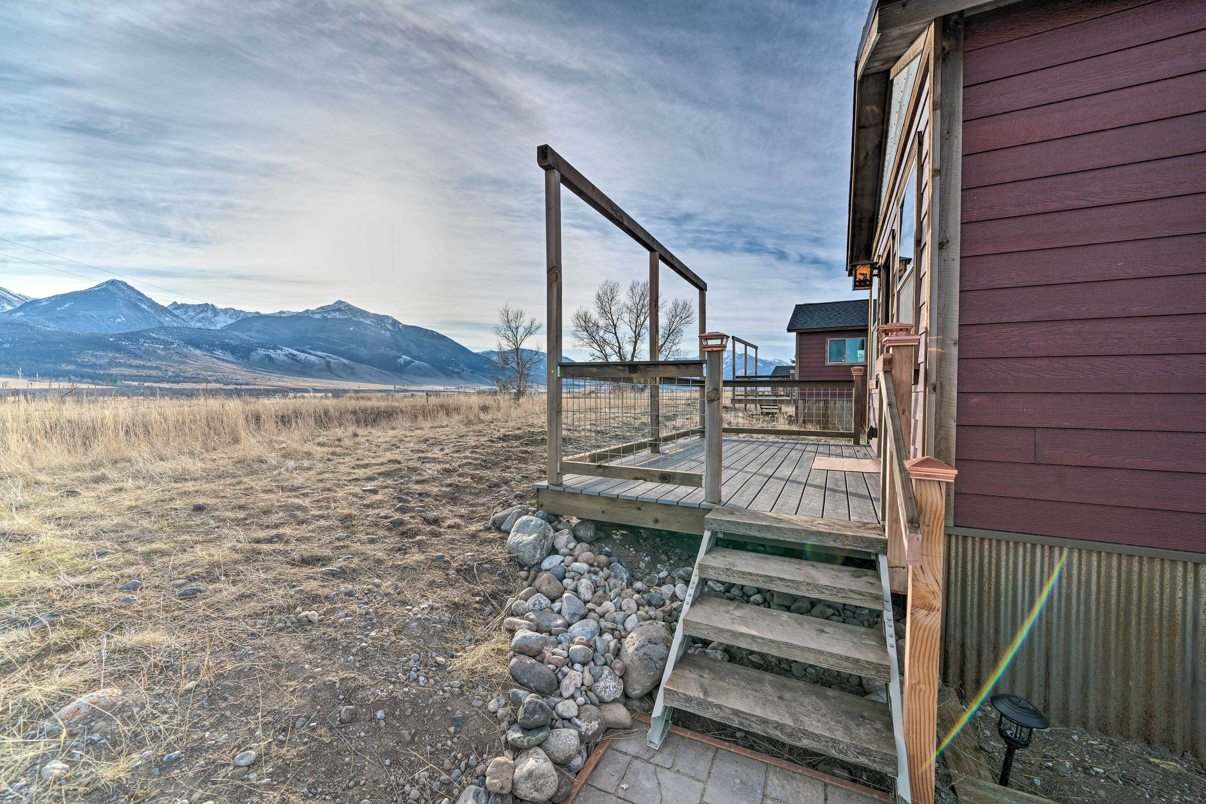 Une terrasse en bois menant à une maison offrant une vue sur les montagnes.