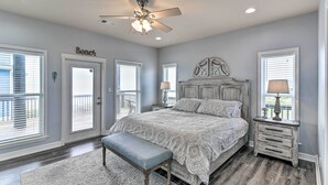 A bedroom with a large bed, a ceiling fan, and a bench. - Group Getaway w/ Deck, Steps to Crystal Beach! (Port Bolivar)