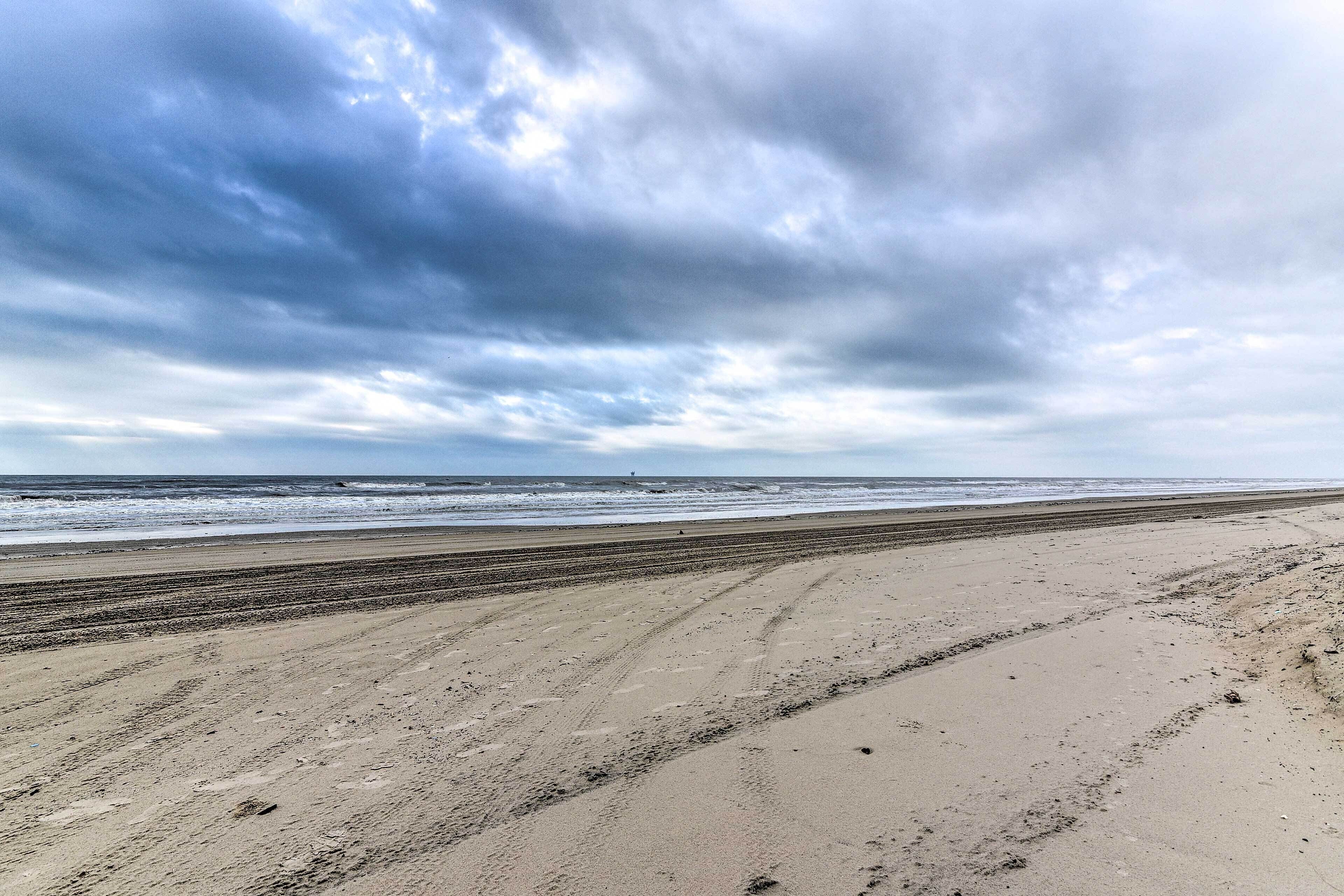A beach with a wide sandy shore and a view of the ocean under a cloudy sky.