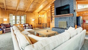 A cozy log cabin interior with a large fireplace, wooden furniture, and a television mounted above it. - Treehouse-style Cabin, 1 Mi to Massanutten Resort (McGaheysville)