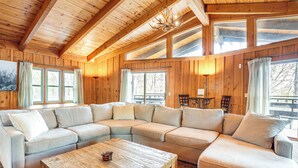 A cozy living room with a large L-shaped sectional sofa, a wooden coffee table, and a chandelier. - Treehouse-style Cabin, 1 Mi to Massanutten Resort (McGaheysville)