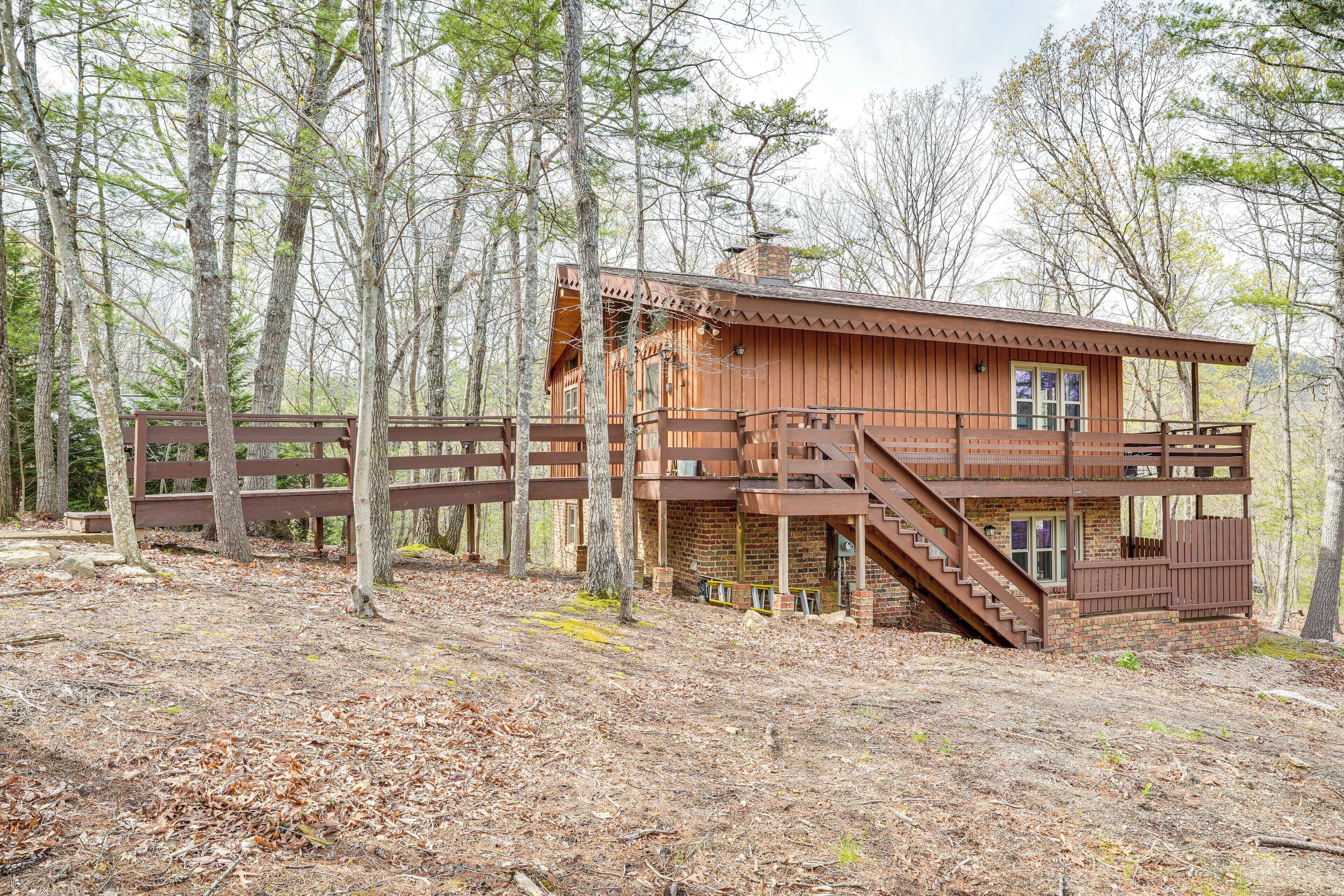 A rustic cabin with a wooden exterior, a balcony, and a staircase leading to the upper level.
