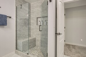 A modern bathroom with a glass-enclosed shower, marble walls, and a visible towel rack. - Waterfront PNW Escape w/ Deck & Beach Access! (Port Hadlock)