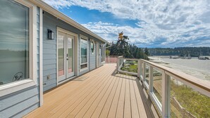 Una terraza de madera con barandilla, ventanas amplias y vista al río.