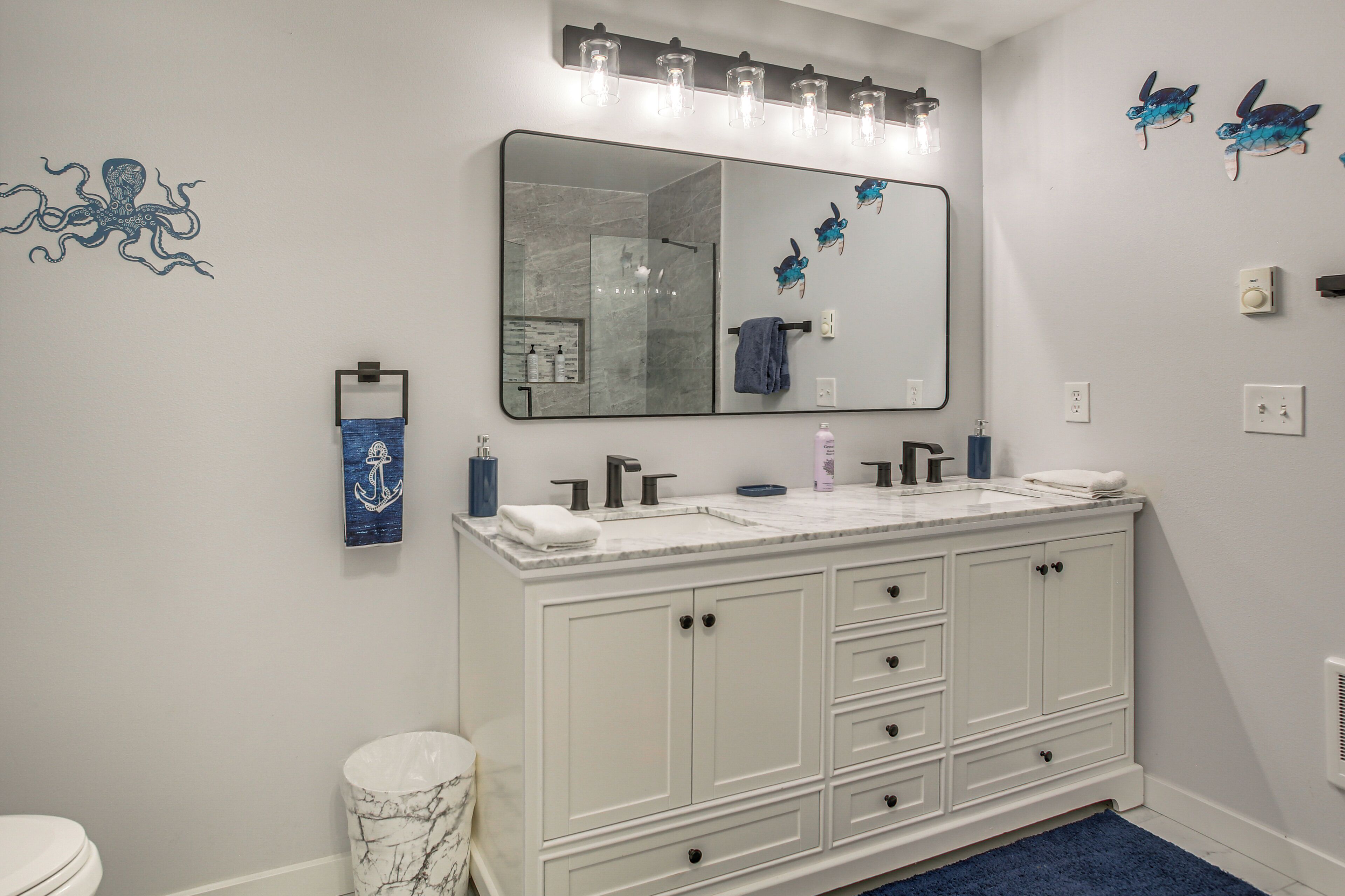A bathroom with a white vanity, a large mirror, and a shower area.