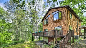 Une cabane en bois dotée d’une terrasse et d’un escalier, entourée d’arbres.