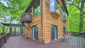 Une cabane en bois dotée d’une terrasse, de grandes fenêtres et d’un espace salon extérieur.