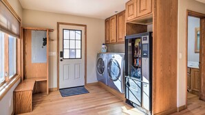 A laundry room with wooden cabinets, a washing machine, a dryer, and a refrigerator.