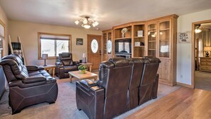 A living room with a sectional sofa, a recliner, a wooden cabinet with glass doors, and a television.