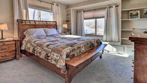 A bedroom with a wooden bed, a nightstand, a bench, and a built-in bookshelf.