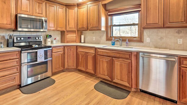A kitchen with wooden cabinets, stainless steel appliances, and a window.