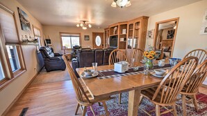 A dining area with a wooden table, chairs, and a patterned rug.