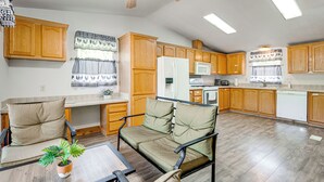 A spacious kitchen with wooden cabinets, a refrigerator, microwave, and dishwasher. There is a dining area with a table and chairs, and a ceiling fan above. - 33 Miles to Yosemite Park Entrance (Mariposa)