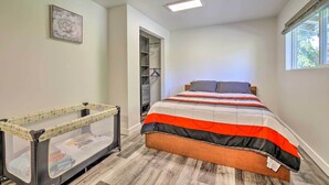 Un dormitorio con cama, cuna, vestidor y ventana.