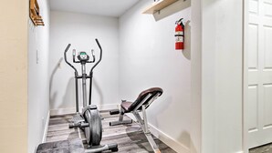 Un gimnasio casero compacto con una bicicleta estática, una elíptica y un banco para press de banca.