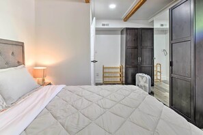 Een slaapkamer met een groot bed, een bedlampje, een kledingkast en een ventilator.