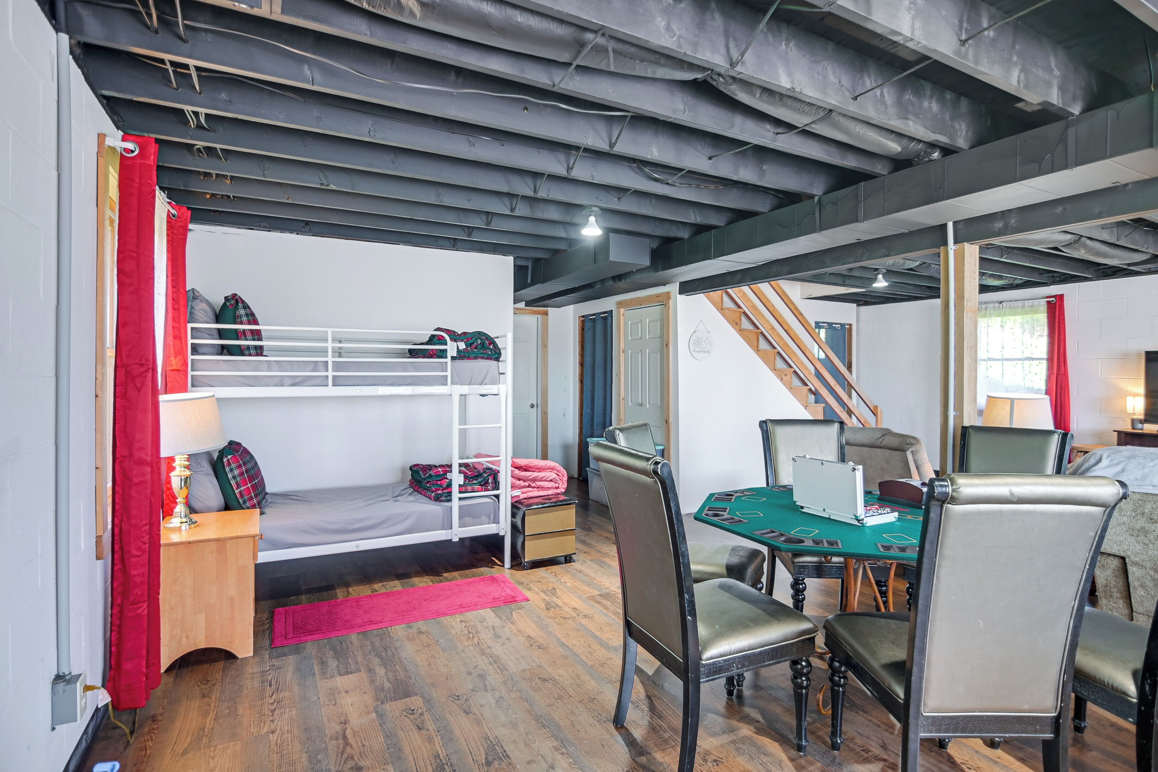 A room with bunk beds, a desk, chairs, and a staircase.