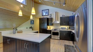 Una cocina moderna con una isla grande, electrodomésticos de acero inoxidable y armarios oscuros.