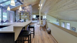 Una cocina amplia con pared de piedra, techo de madera y ventanas grandes.