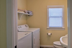 A laundry room with a washer and dryer, a shelf with folded clothes, a window with blinds, and a toilet. - Secluded & Quiet Atlantic Home: 1 Mi to Boat Ramp! (Atlantic)